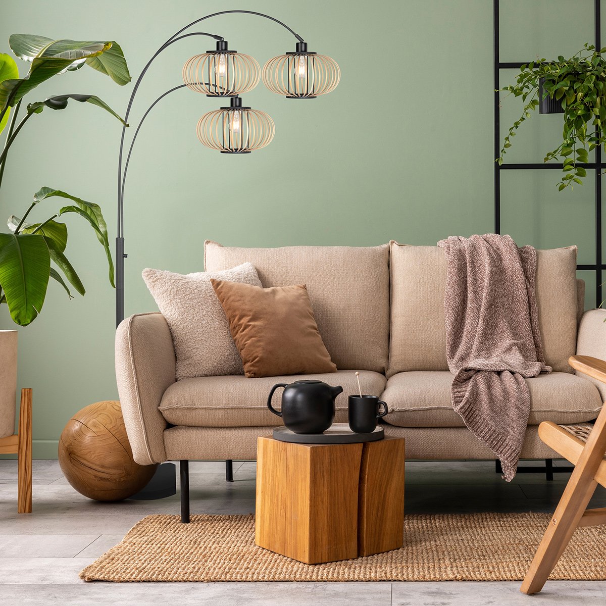 Mise en ambiance salon : lampadaire allumé devant un canapé beige, mur vert