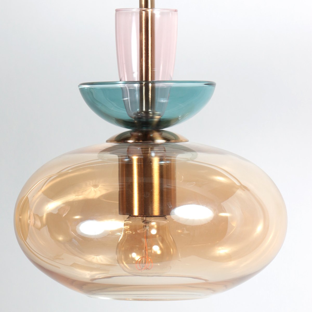 Gros plan sur les petits verres rose et bleu pétrole empilés au-dessus du diffuseur.