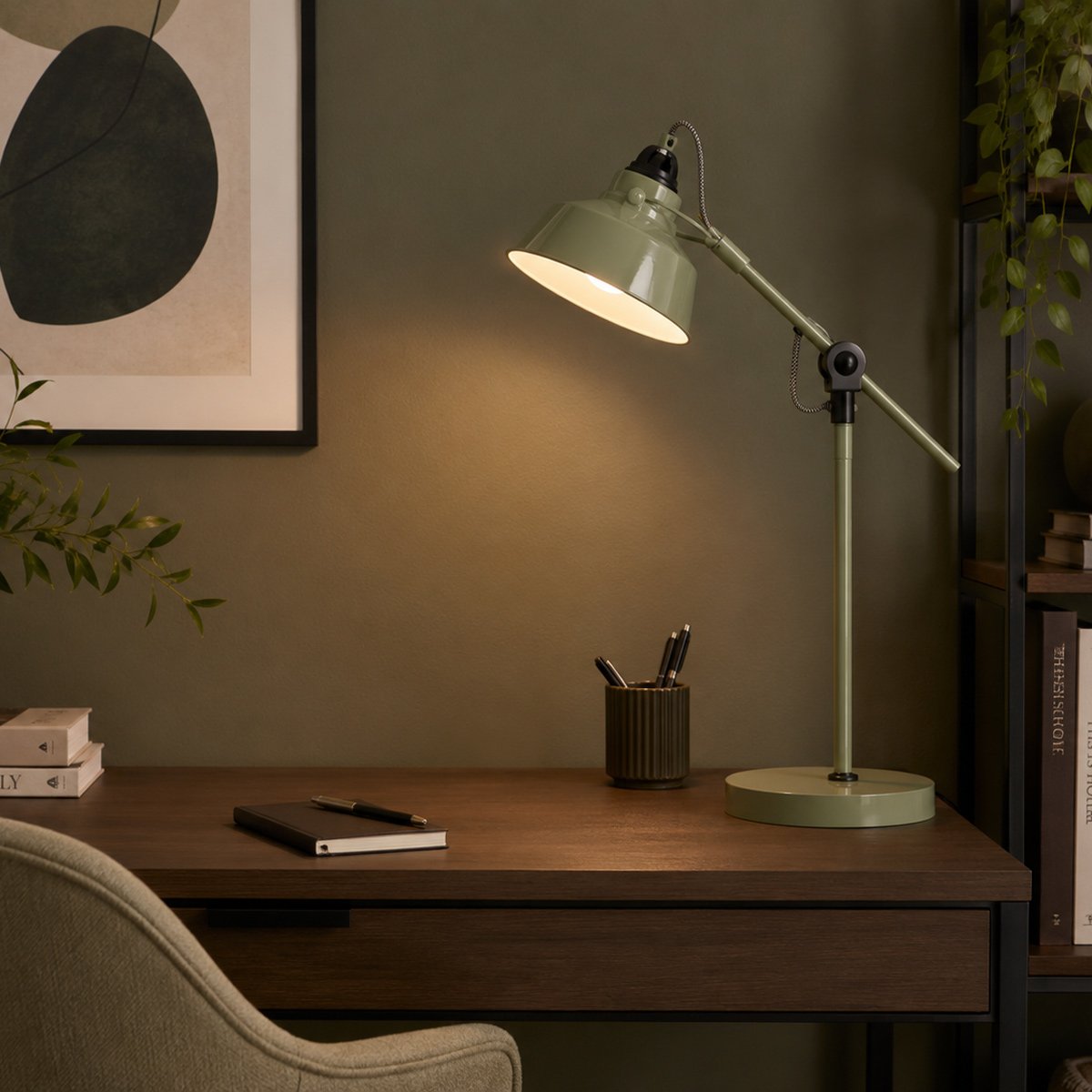 Ambiance chaleureuse sur bureau en bois foncé, lampe allumée près de cadres et livres.