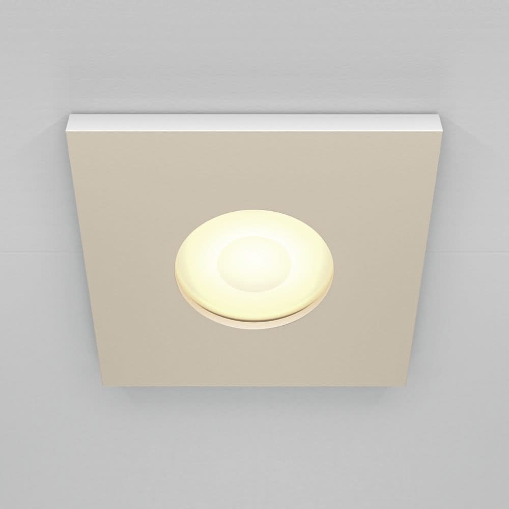 Spot encastré à plaque carrée beige et diffuseur rond allumé au centre