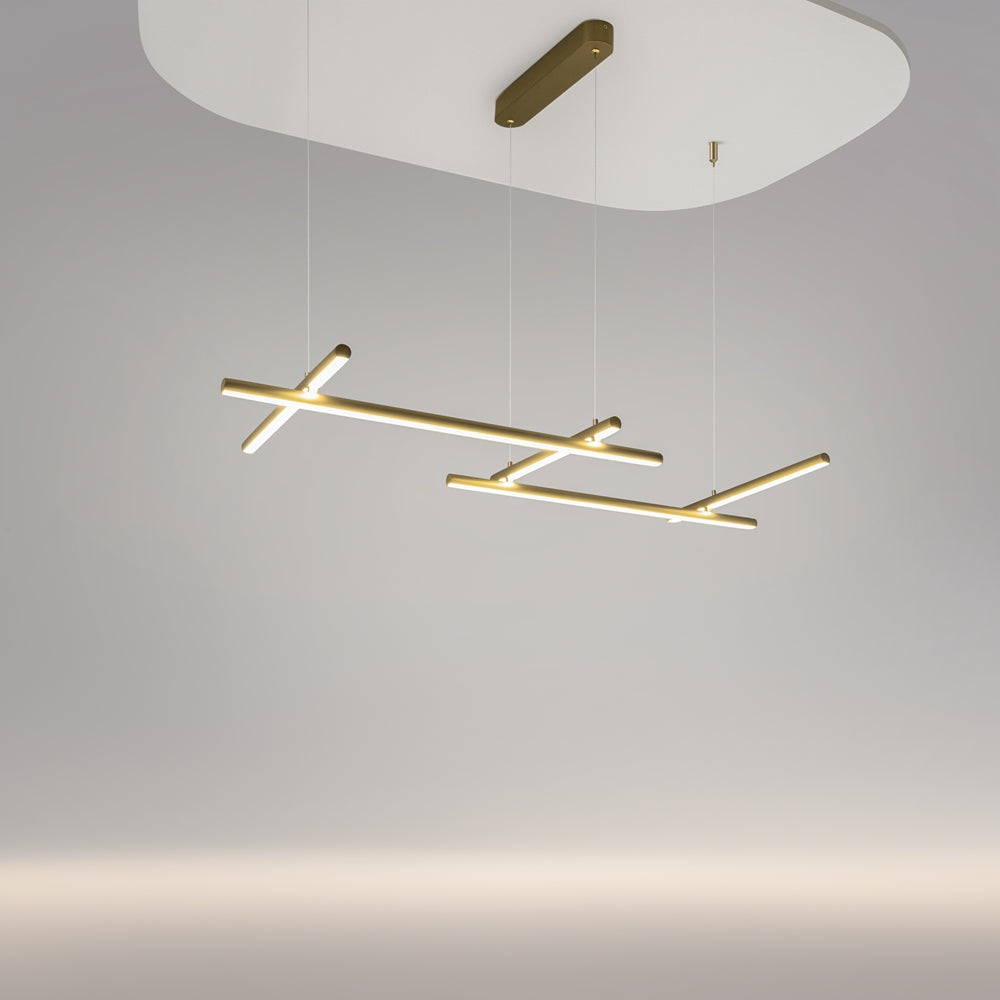 Vue en contre-plongée du luminaire suspendu, tubes dorés croisés sous un plafond blanc.