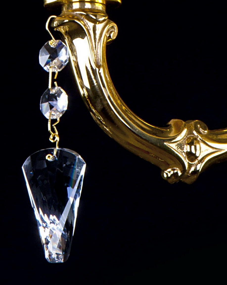Détail du pendant de cristal taillé suspendu au bras en laiton doré sculpté