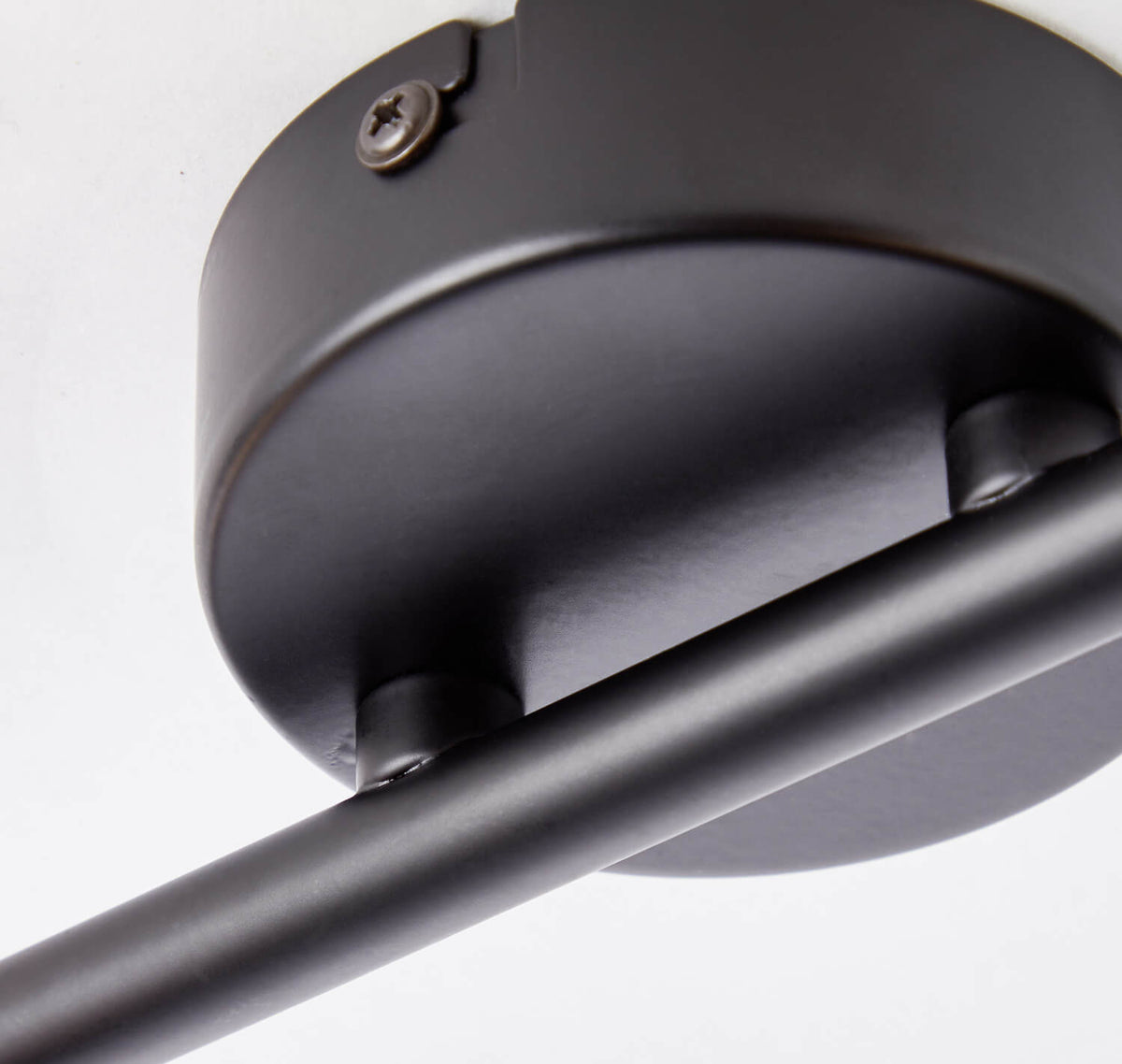 Détail de la base noire fixée au plafond avec vis apparentes et finition mate