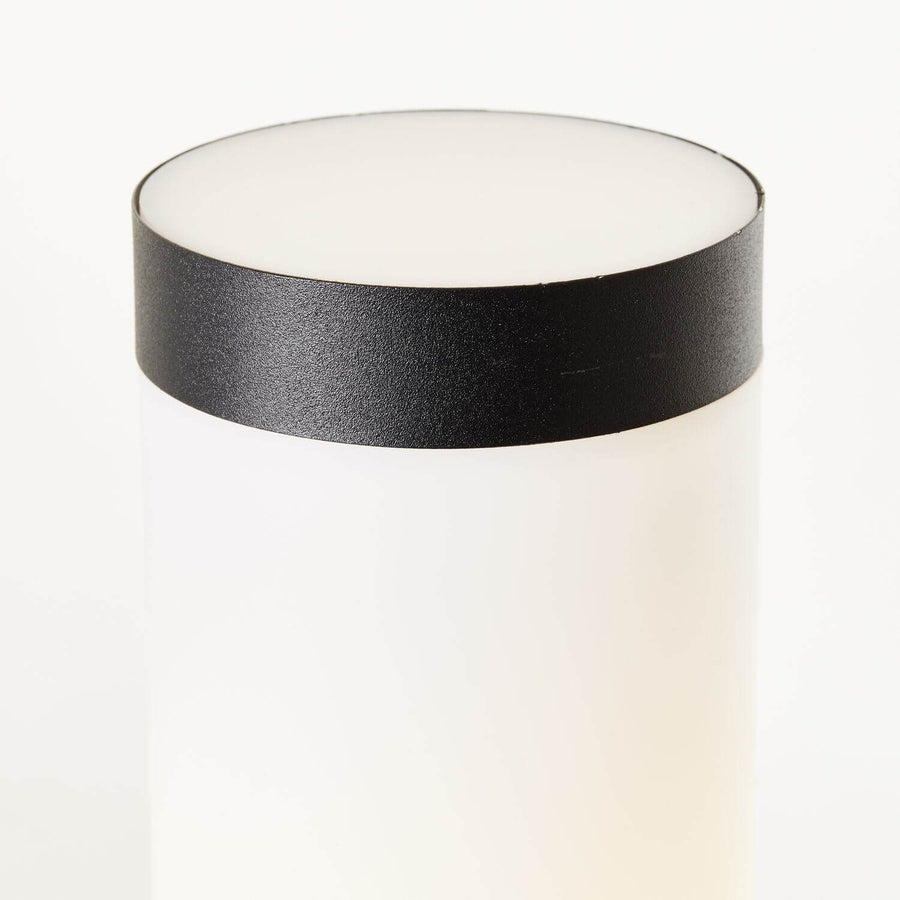 Détail du chapeau noir et du haut du diffuseur blanc cylindrique.