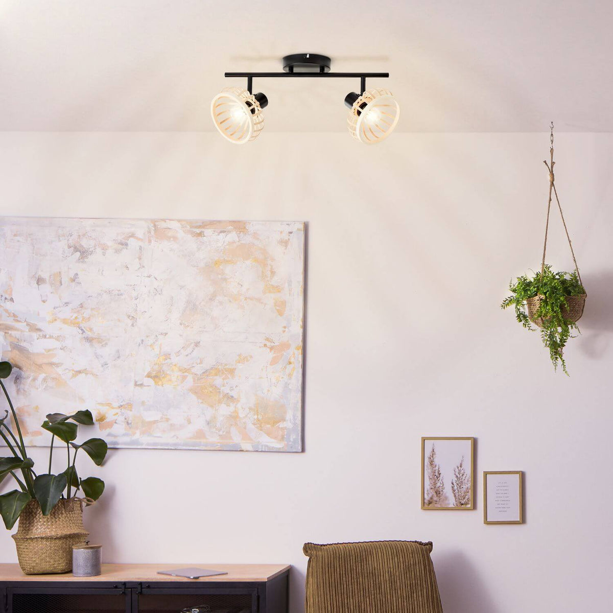 Mise en ambiance salon bohème avec tableau, plantes vertes et suspension murale