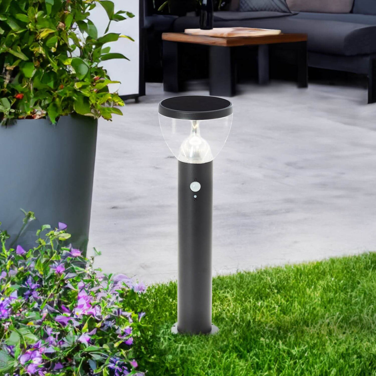 Mise en ambiance dans un jardin, borne allumée entre gazon et plantes