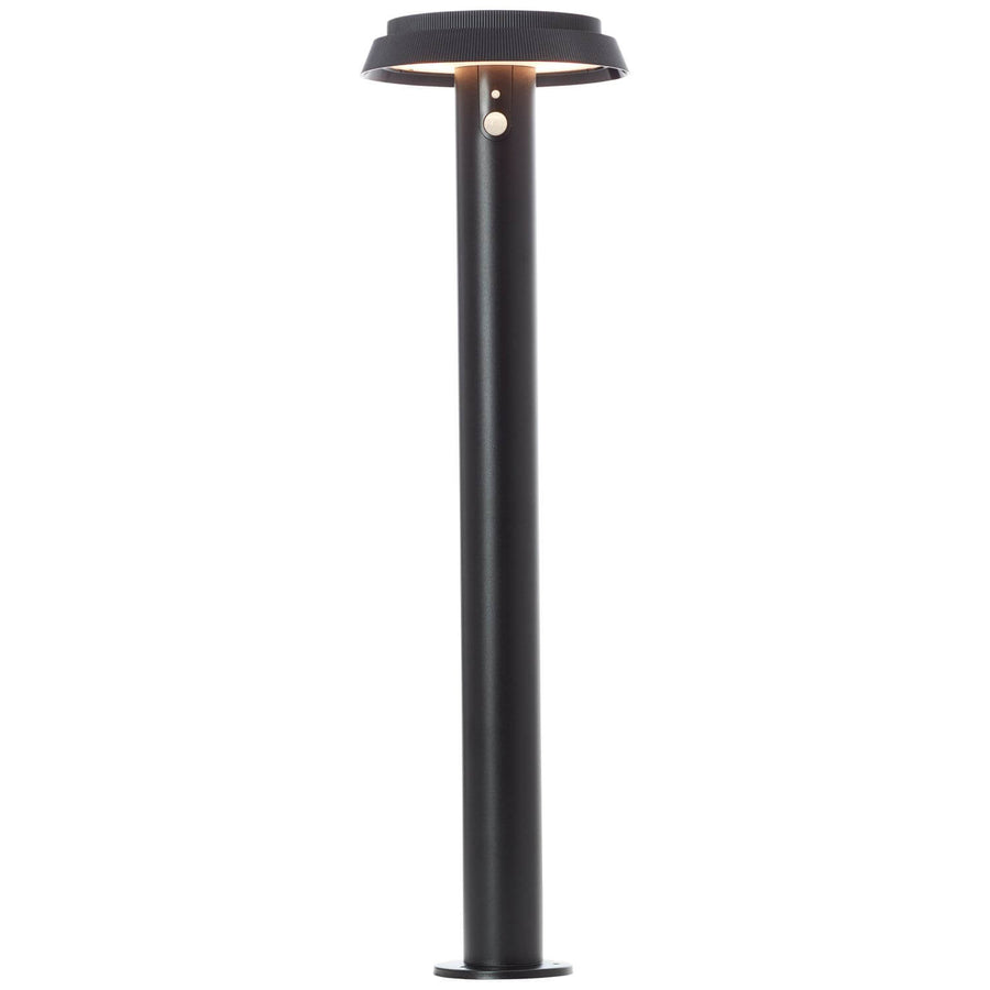 Lampadaire allumé de face, halo lumineux diffus sous le chapeau circulaire noir.