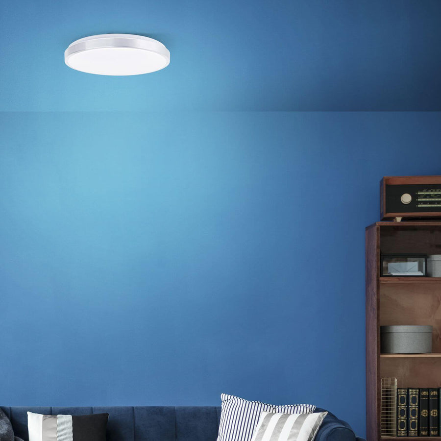 Plafonnier allumé fixé au plafond bleu, au-dessus d'une bibliothèque en bois.