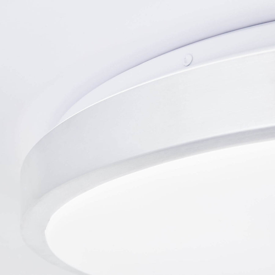 Détail rapproché du bord métallique et du diffuseur blanc translucide du plafonnier.