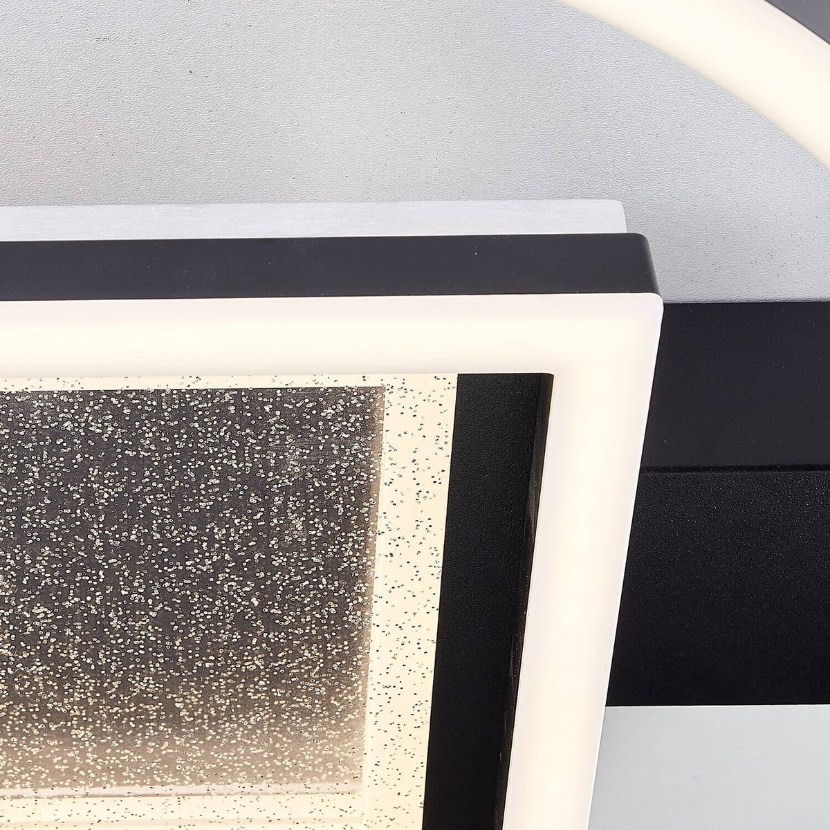 Détail de la finition : cadre noir mat, liseré blanc et verre moucheté du diffuseur