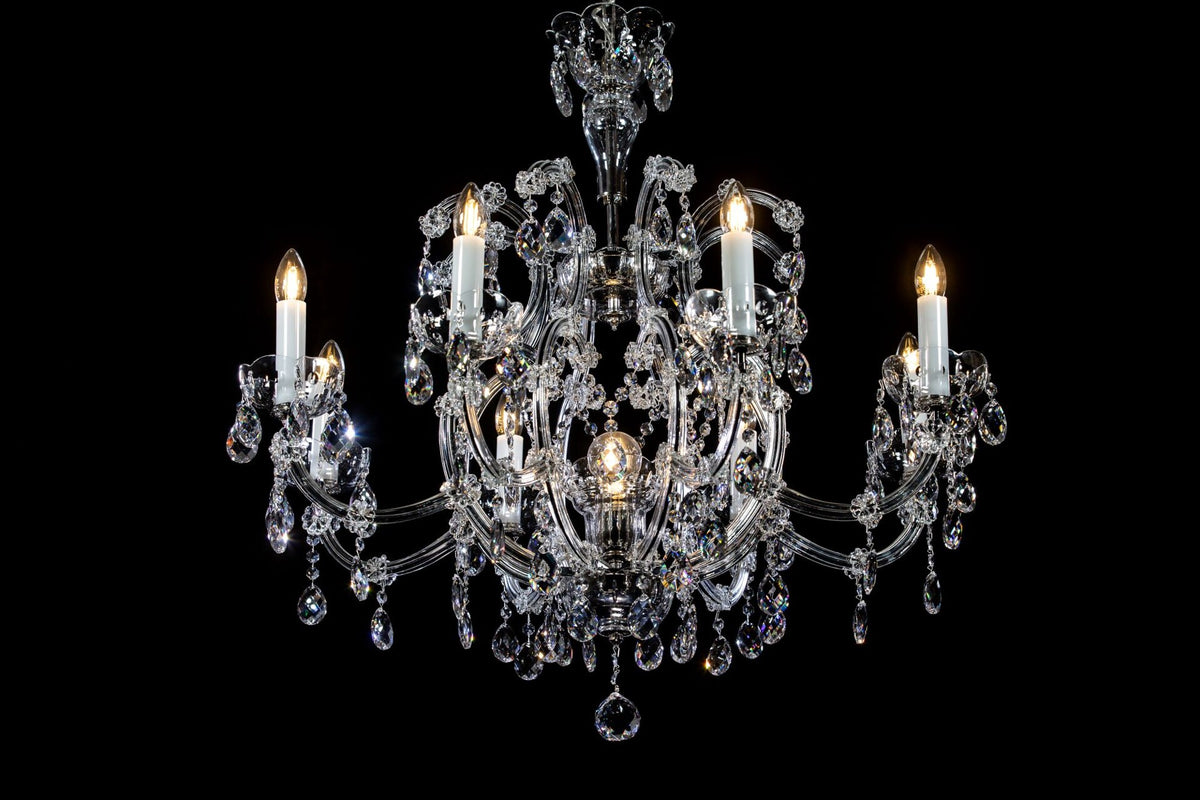 Lustre en cristal vu de face, bras recourbés et pendeloques sur fond noir