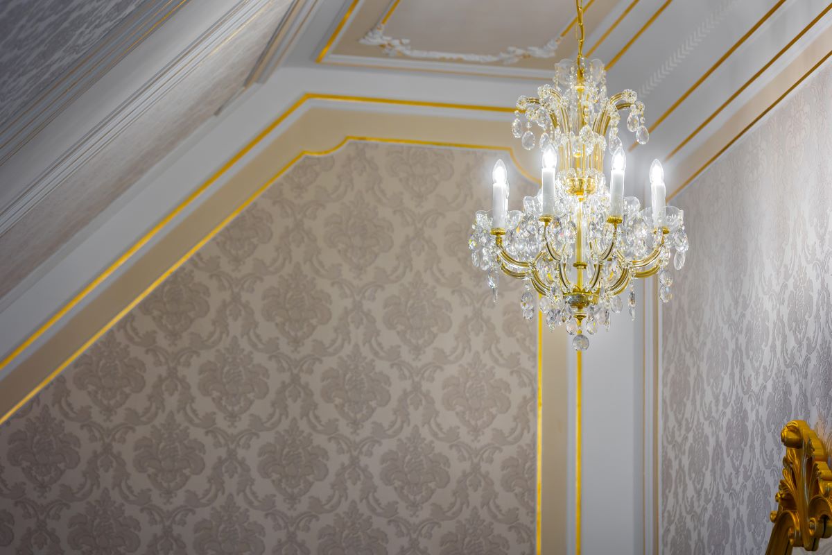 Vue en contre-plongée du lustre suspendu dans une pièce moulurée, montrant son raccord au plafond