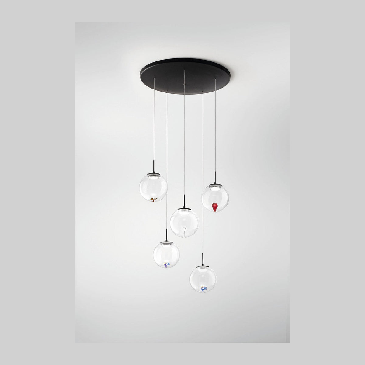 Vue de face du luminaire suspendu, cinq globes de verre transparents à hauteurs variables