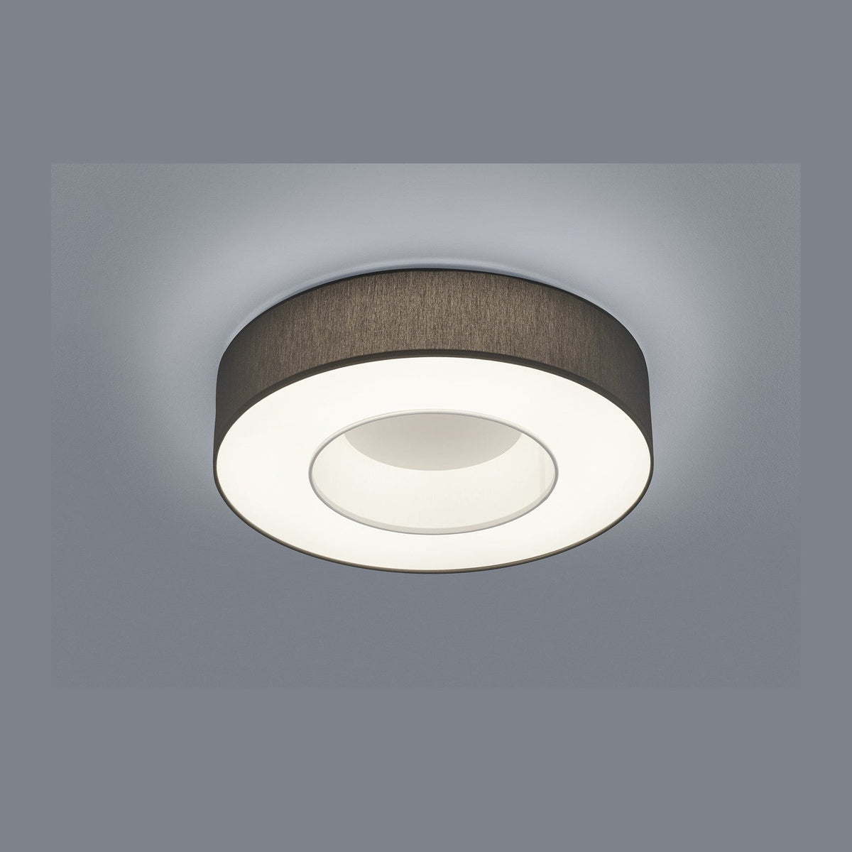 Plafonnier rond blanc vu de trois quarts, bandeau textile beige et diffuseur lumineux.