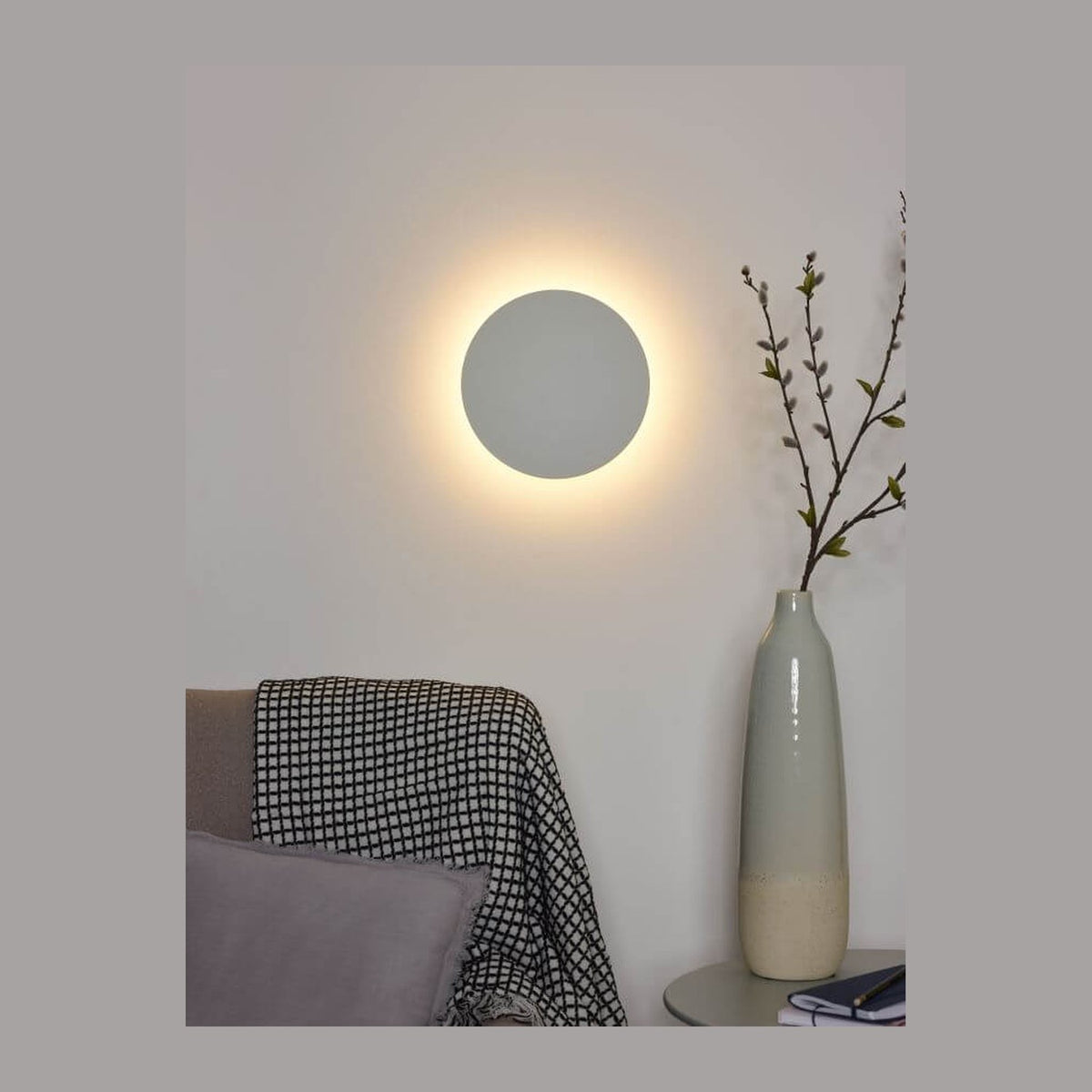 Applique murale ronde blanche fixée au mur, halo lumineux diffus dans un salon