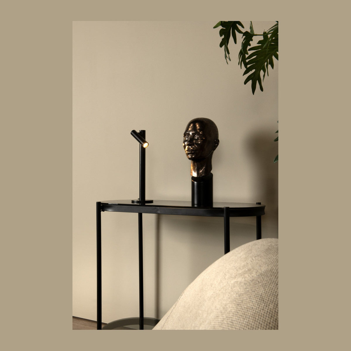 Lampe à poser noire sur une console, près d'un buste sculpté
