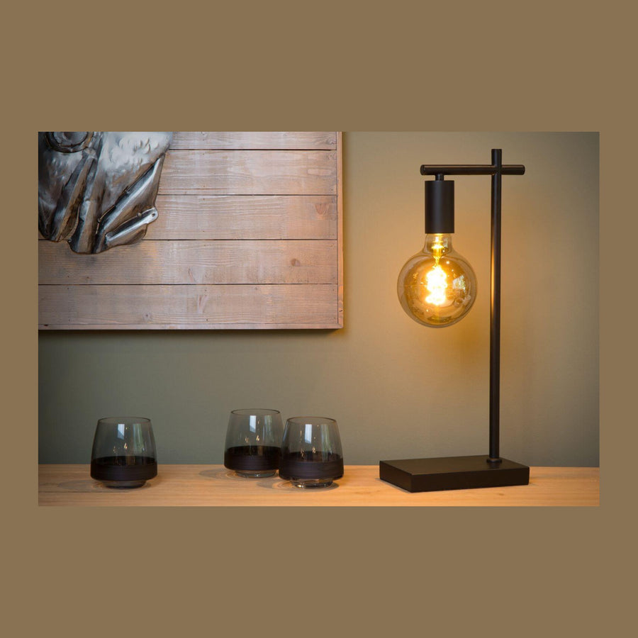 Lampe à poser noire sur console en bois, verres et mur vert olive