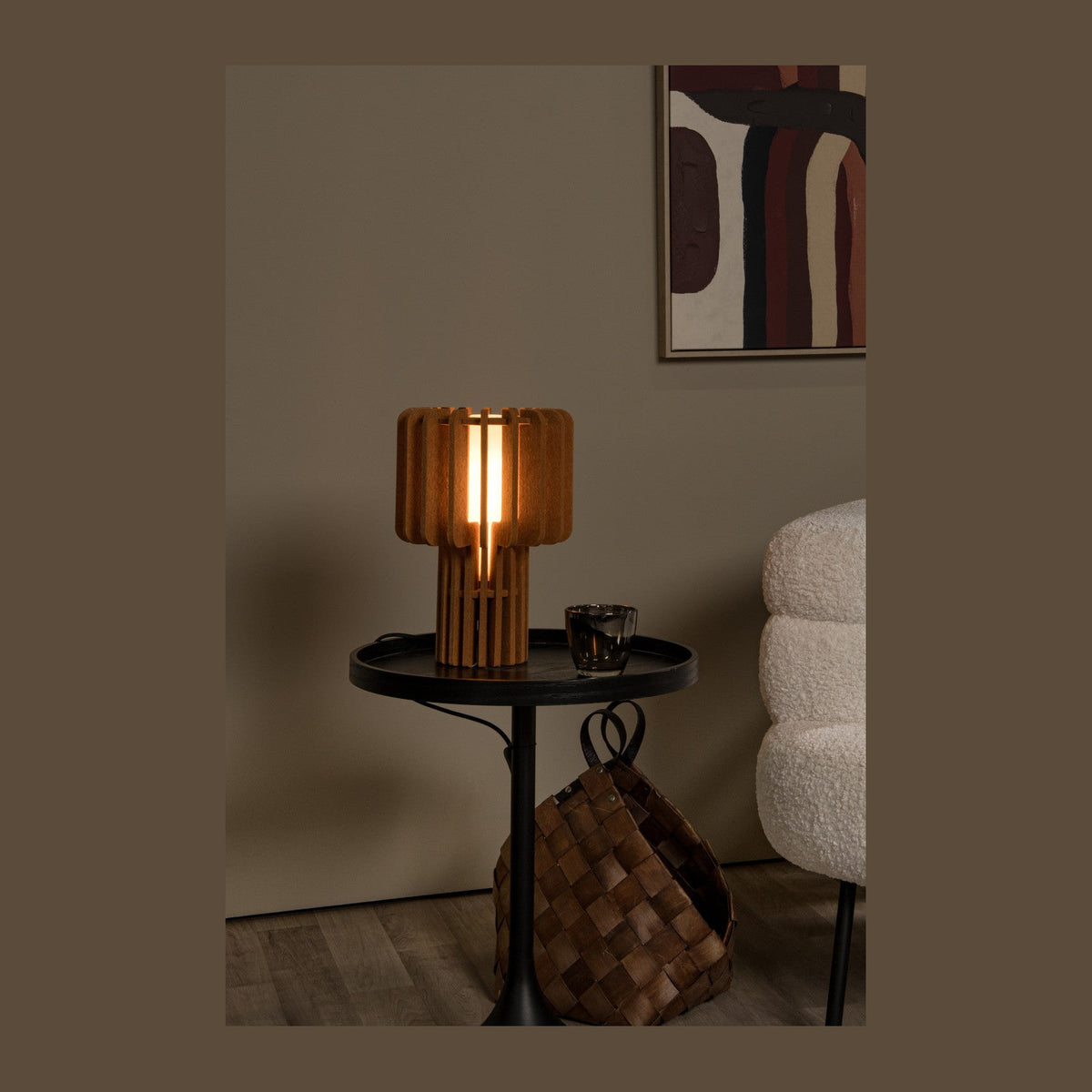 Lampe à poser en bois allumée, posée sur table d'appoint noire en mise en ambiance