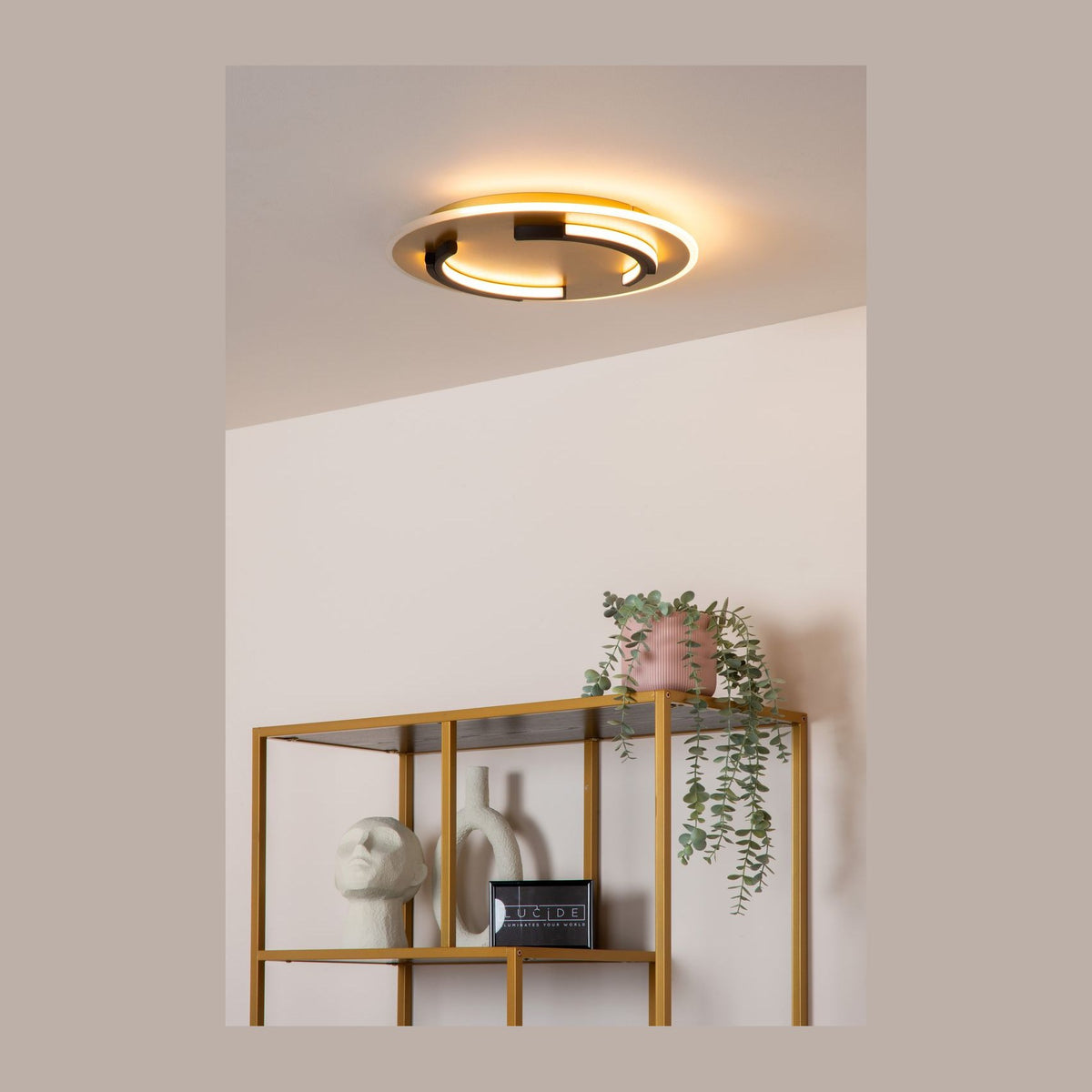 Plafonnier doré allumé au plafond au-dessus d'une étagère déco dans un intérieur clair