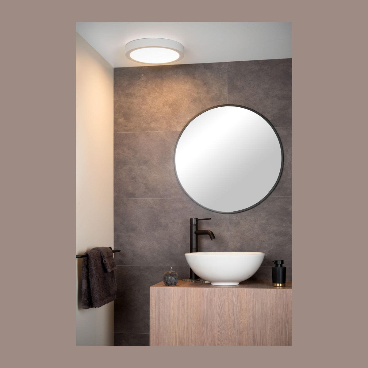 Mise en ambiance d'une salle de bain moderne avec plafonnier rond allumé au plafond