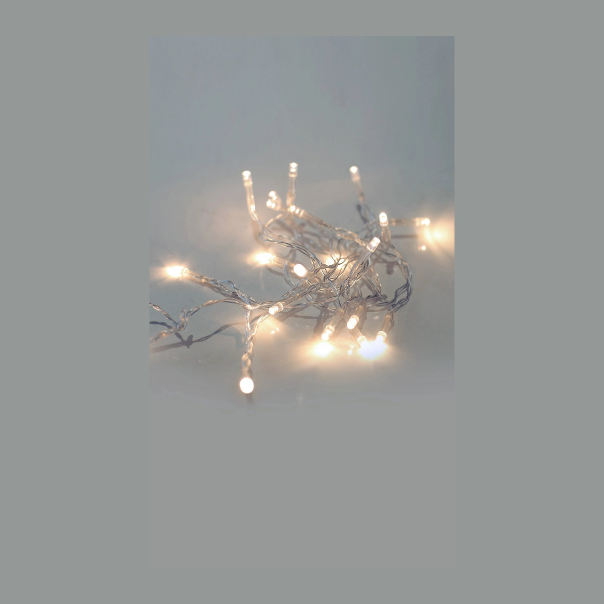 Guirlande lumineuse enroulée sur fond gris, ampoules LED allumées en lumière chaude