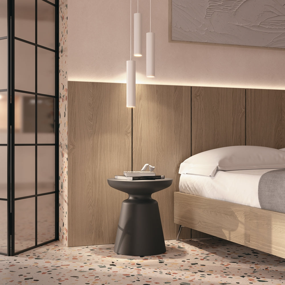 Mise en ambiance chambre, trois suspensions cylindriques au-dessus d'une table de chevet noire