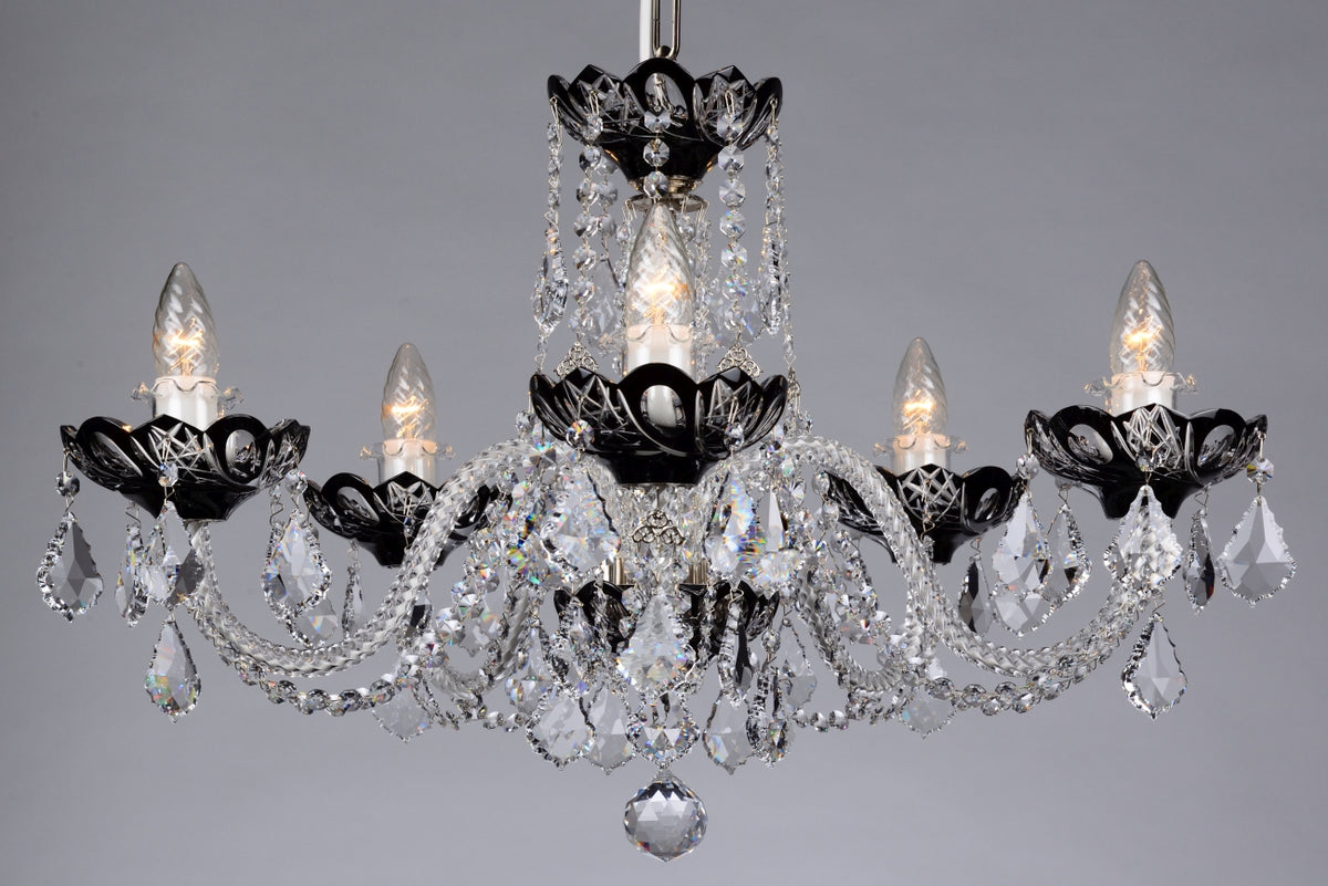 Lustre en cristal à cinq bras lumineux, structure noire et pendeloques scintillantes sur fond gris.