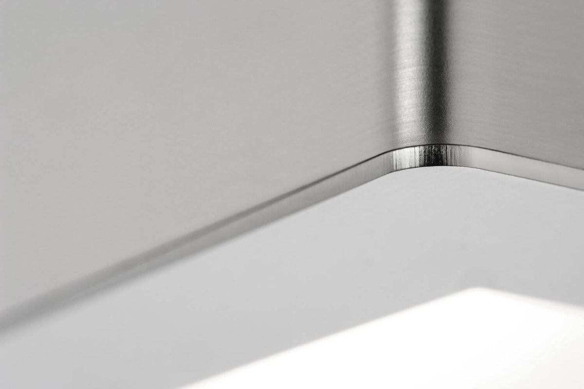 Détail du coin en inox brossé et du diffuseur LED allumé de l'applique murale