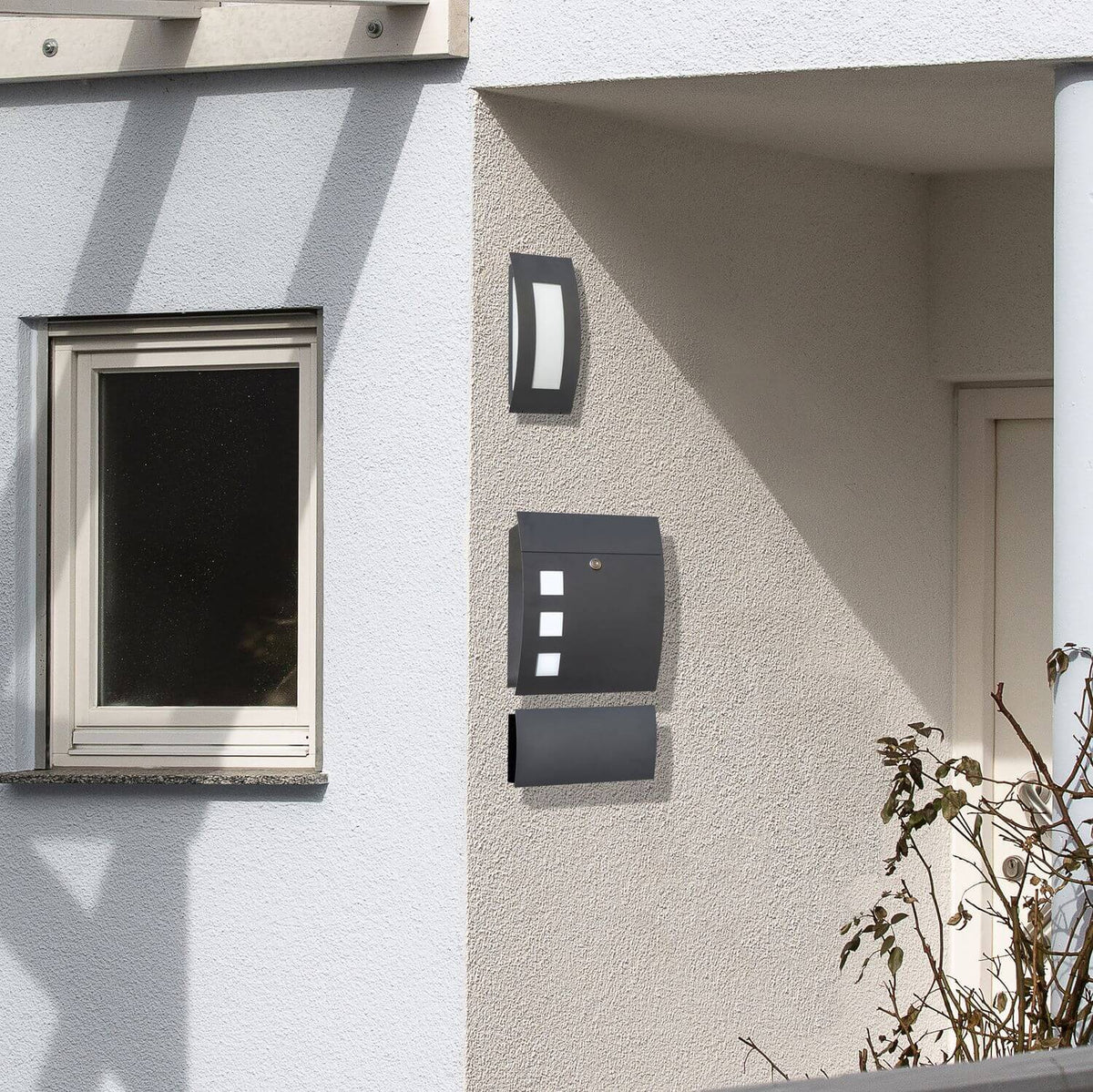 Vue d'ensemble de l'applique anthracite fixée sur une façade extérieure claire, près d'une fenêtre