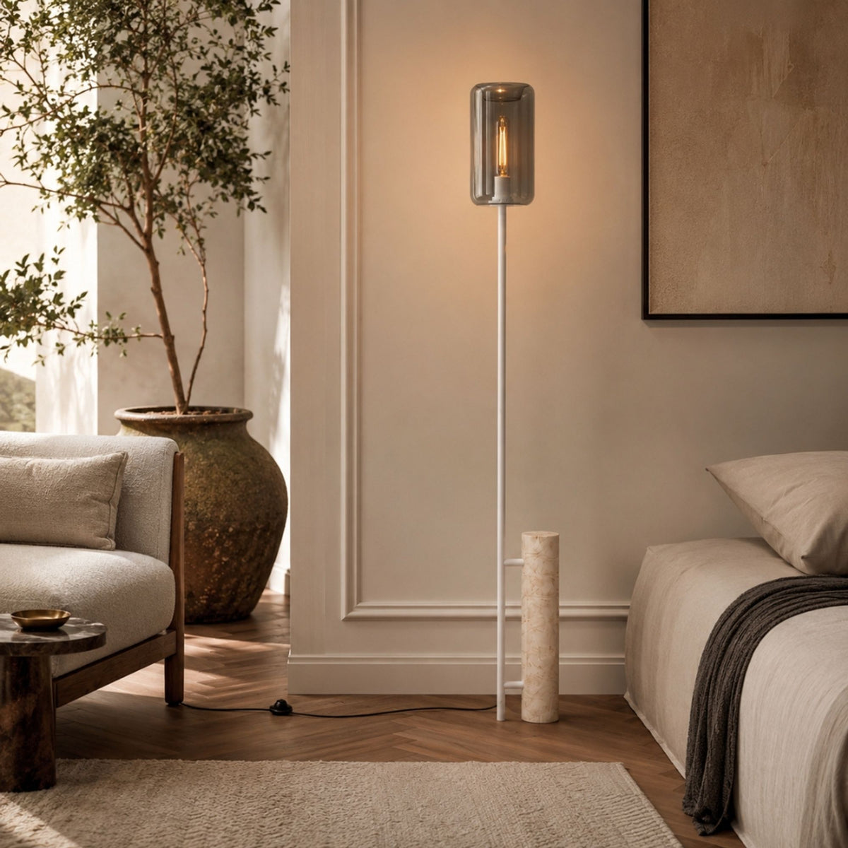 Lampadaire à pied cylindrique en travertin et abat-jour en verre fumé près d'un lit