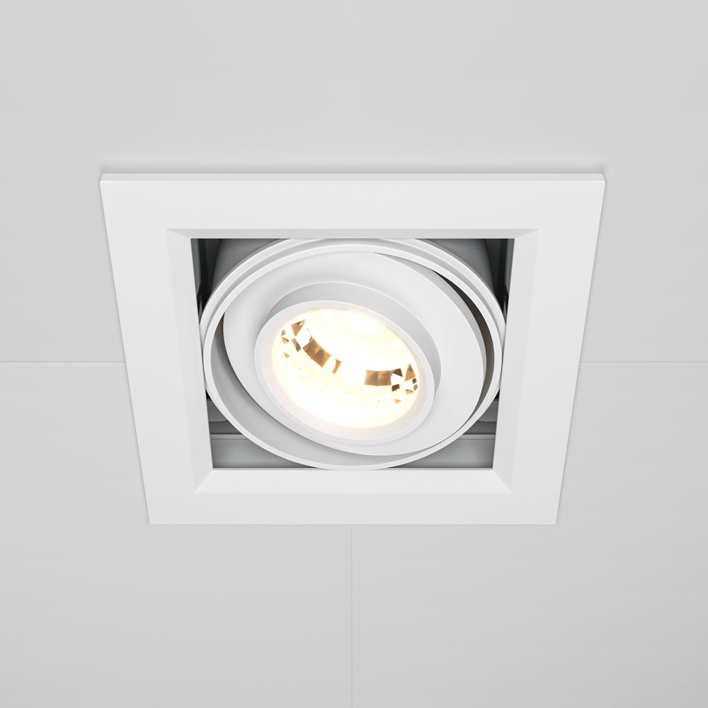 Vue de face d'un spot encastré carré blanc allumé dans un plafond