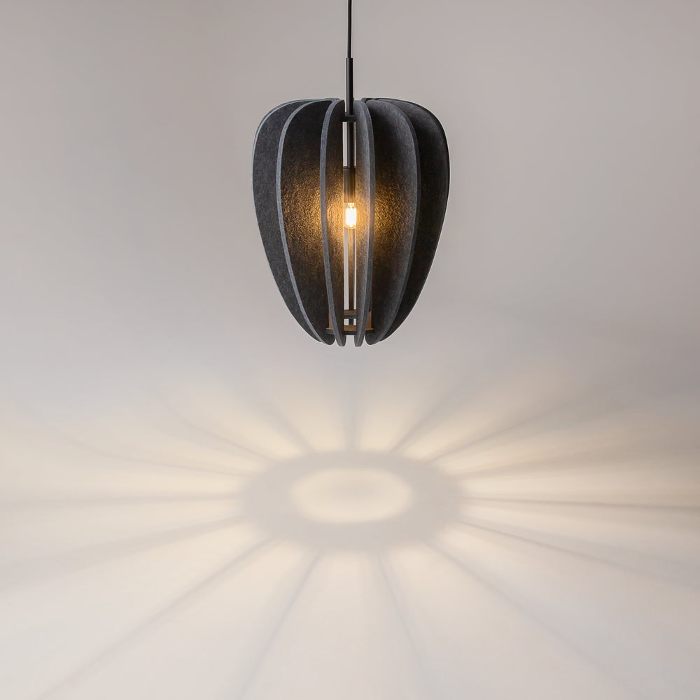 Gros plan du luminaire allumé, ombres rayonnantes projetées sur le mur beige.
