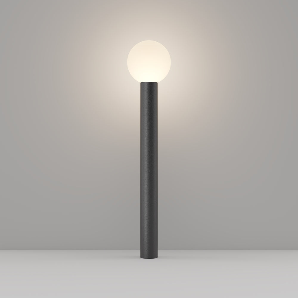 Lampe colonne noire surmontée d'un globe lumineux, posée verticalement au sol