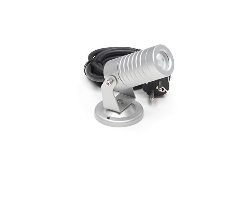 Spot orientable argenté posé sur fond blanc, câble noir enroulé à l’arrière-plan