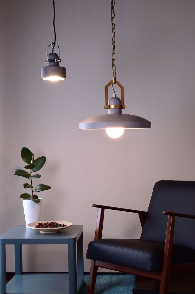 Mise en ambiance avec deux suspensions allumées au-dessus d’une table et d’un fauteuil.