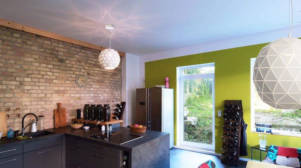 Mise en ambiance dans une cuisine moderne avec deux suspensions blanches géométriques allumées.