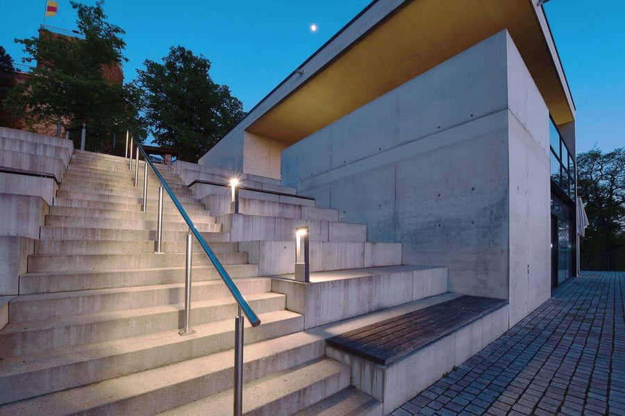 Autre vue extérieure au crépuscule, lampadaire aligné le long d’un escalier en béton.