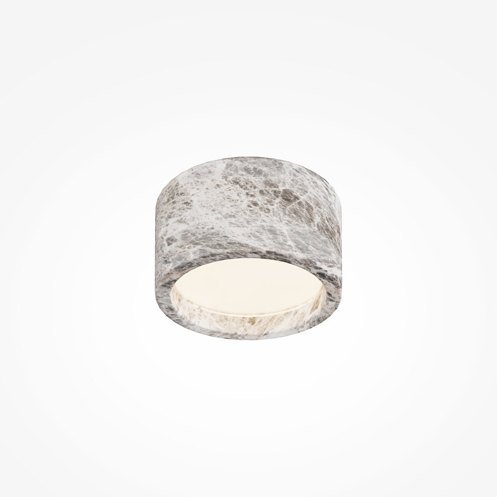 Vue rapprochée du cylindre blanc, ouverture lumineuse et matière craquelée effet marbre.
