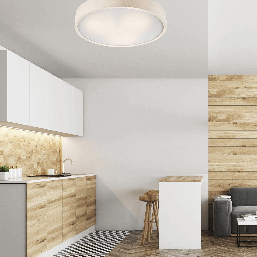 Plafonnier allumé au-dessus d'une cuisine moderne aux meubles en bois clair.