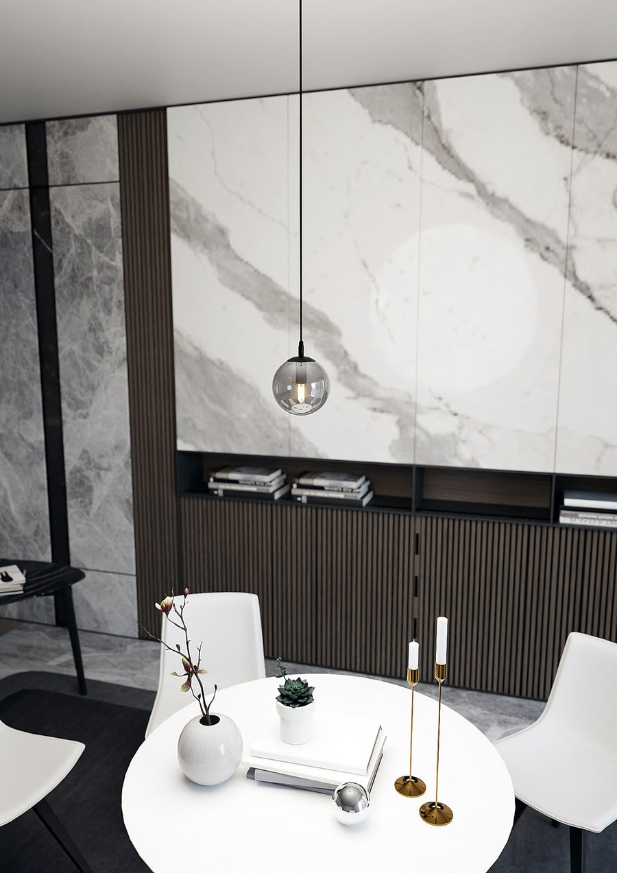 Globe suspendu au-dessus d'une table ronde décorée, devant un mur en marbre et bois.