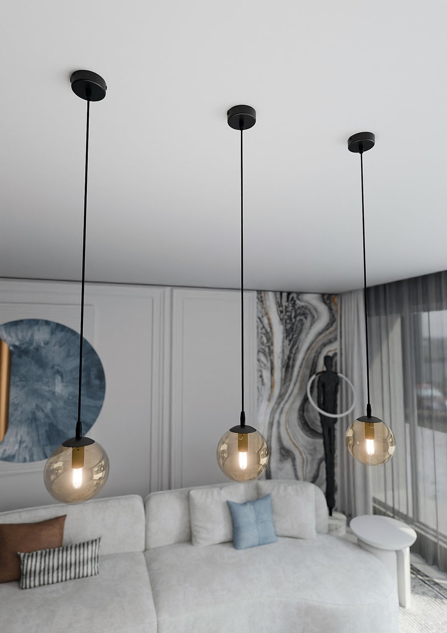 Trois globes ambrés suspendus devant un mur décoratif, vue en contre-plongée.