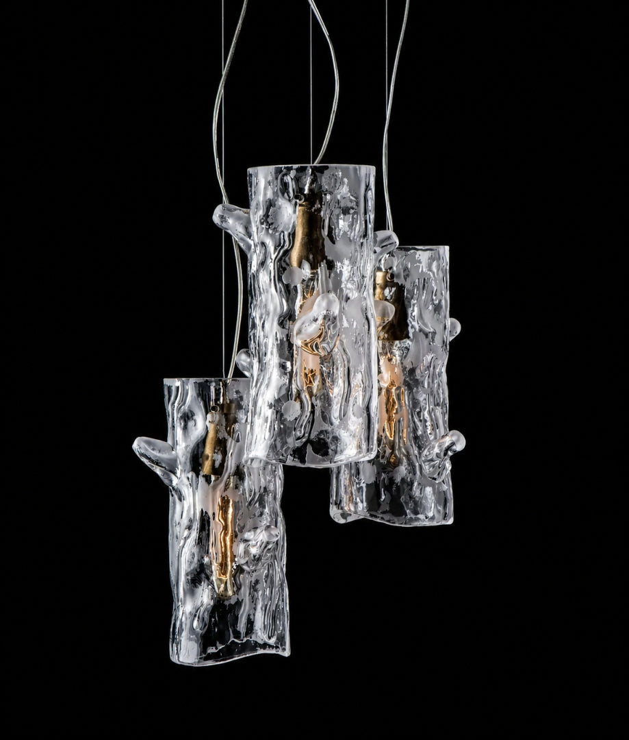 Trois suspensions en verre transparent texturé, forme de tronc d'arbre, sur fond noir