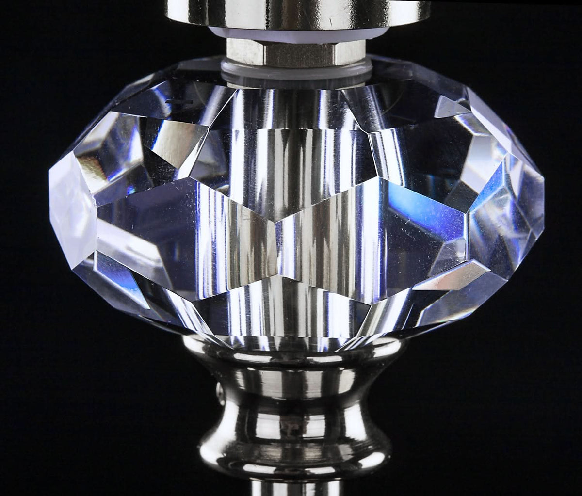 Détail rapproché du cristal facetté et des reflets sur la tige métallique polie.