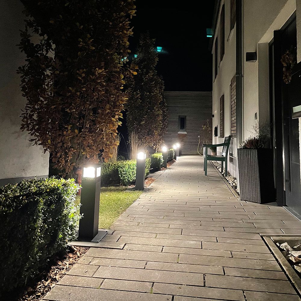 Allée de jardin éclairée la nuit par des bornes basses alignées le long des haies