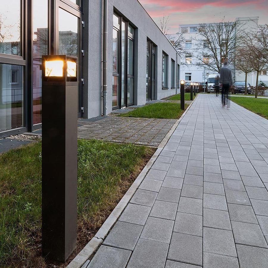 Plusieurs bornes alignées sur un trottoir au crépuscule devant un bâtiment