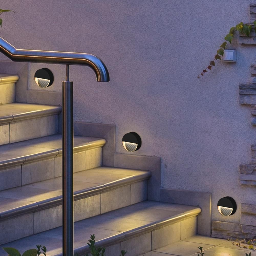 Mise en ambiance nocturne sur un mur d'escalier extérieur, trois appliques allumées