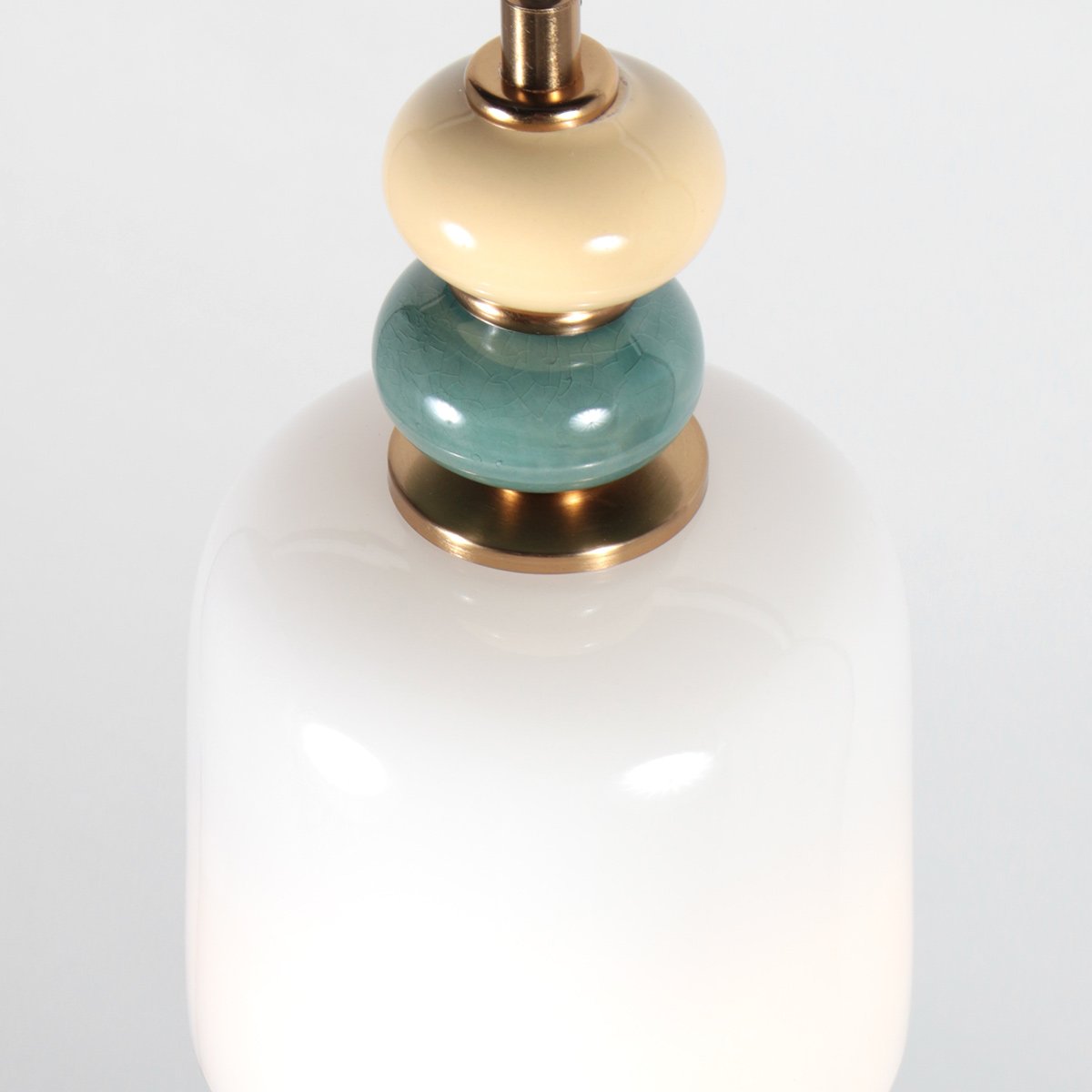 Détail rapproché des perles céramique beige et bleu-vert sur bagues en laiton