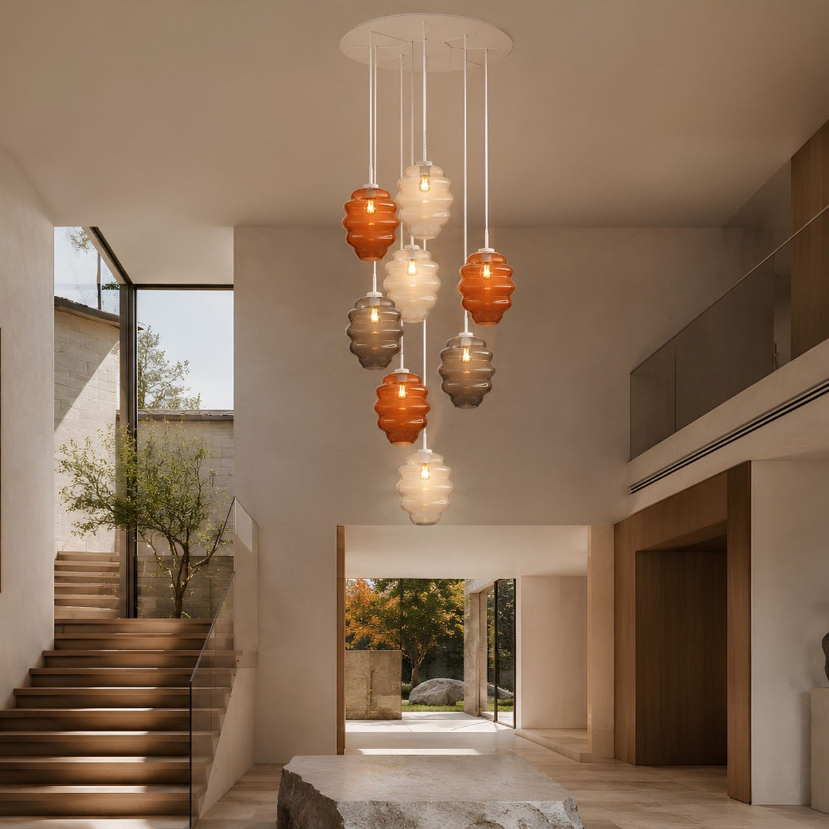 Suspension en verre coloré éclairant un grand volume avec escalier et vue sur jardin