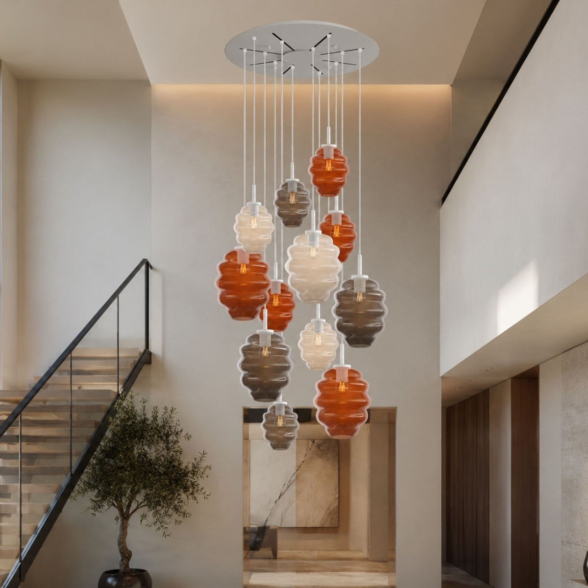 Suspension installée dans un grand escalier, verres orange, blancs et gris suspendus.