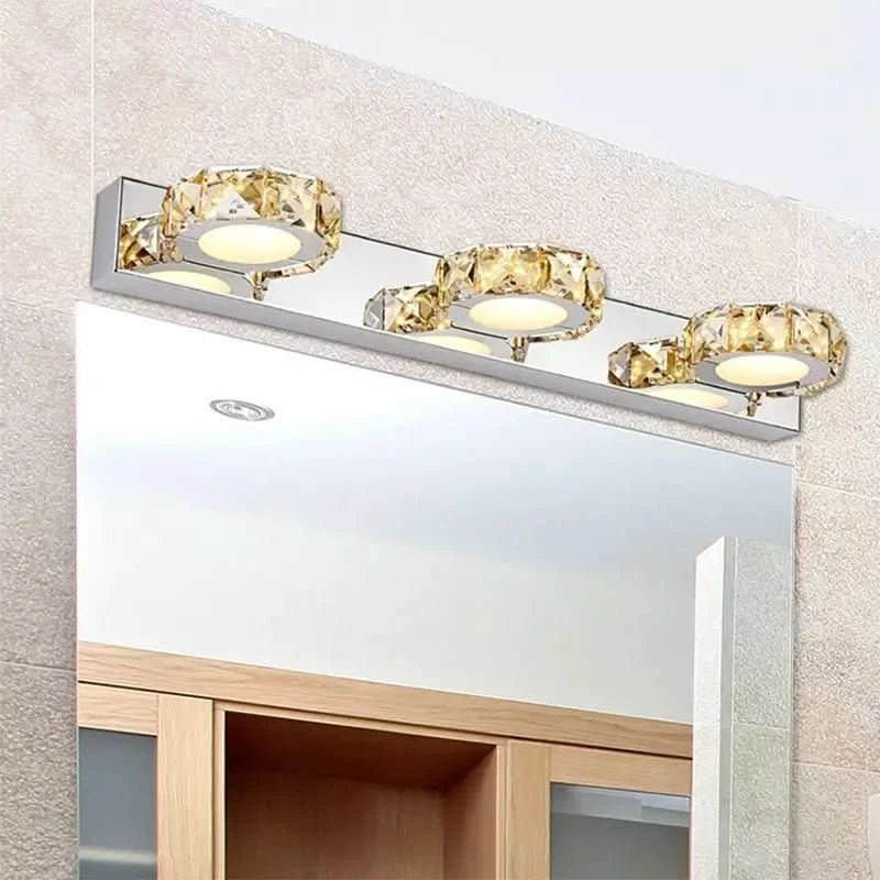 Applique murale à trois cercles de cristal installée au-dessus d'un miroir de salle de bain